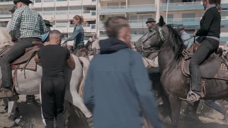 Cinematic-slow-motion-shot-of-majestic-stride-of-horses-with-their-riders-on-beach-during-Feria-Palavas-parade