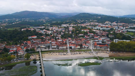 Stunning-aerial-4K-drone-footage-of-a-village---Ponte-de-Lima-in-Portugal-and-its-iconic-landmark---Stone-roman-bridge-crossing-over-the-Lima-River