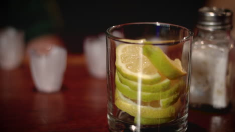 A-captivating-scene-of-a-whiskey-glass-sitting-on-a-bar-counter,-containing-only-slices-of-lemon