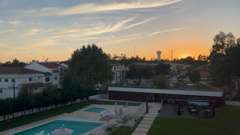 Sunset-timelapse-above-fancy-hotel-poolside-with-cars-zooming-by-outside-fence