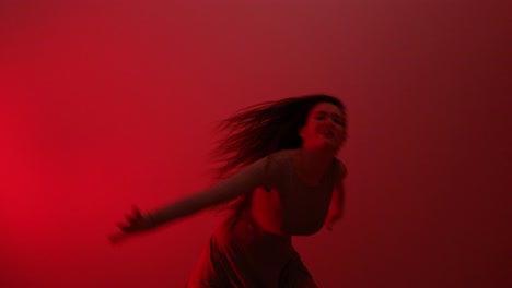 Young-artistic-woman-expressing-herself-in-blood-red-room-dancing