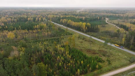Establishing-aerial-view-of-the-autumn-forest,-yellow-leaves-on-trees,-idyllic-nature-scene-of-leaf-fall,-autumn-morning,-highway-with-cars,-wide-drone-shot-moving-forward