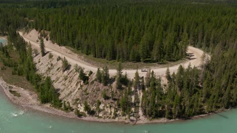 Drone-shot-of-a-pickup-truck-driving-into-the-wilderness-of-Kootenay-National-Park-on-a-logging-road-beside-the-Kootenay-River