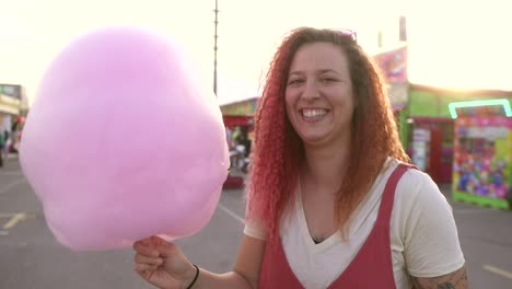 woman-smiles-and-dances-excitedly-with-her-cotton-candy-at-the-fair