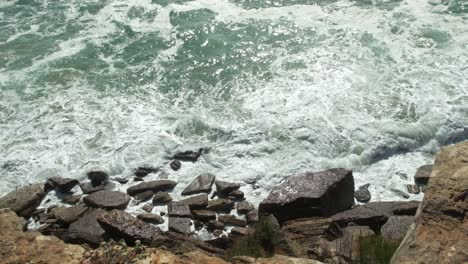 Like-white-foam,-ocean-water-crashes-across-rocky-coastline