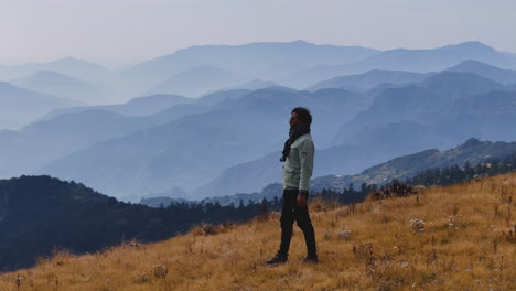 Eine-Drohnenaufnahme-Eines-Männlichen-Touristen,-Der-Von-Der-Aussicht-Aus-Der-Hügellandschaft-Nepals-Beeindruckt-Ist-Und-Details-Der-Ruhigen-Schönheit-Der-Natur-Wahrnimmt