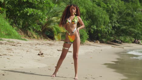 A-girl-in-a-body-tape-bikini-and-long-curly-hair-stands-on-a-tropical-Caribbean-beach-sunny-day