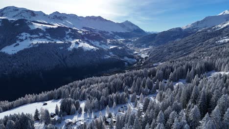 Aerial-flyover-snowy-mountains-and-forest-landscape-with-Brambrüesch-Village-in-the-valley,-Chur,-Switzerland---Panorama-view