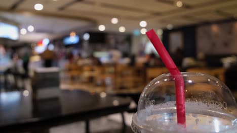 Closer-capture-of-the-Red-Straw-in-a-Plastic-Disposable-Cup-in-a-restaurant-in-Bangkok,-Thailand