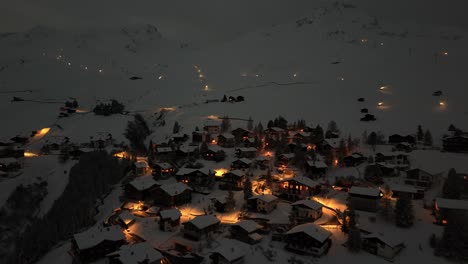 Aerial-approaching-shot-of-Arosa-Town-on-snowy-mountain-at-night-in-Switzerland