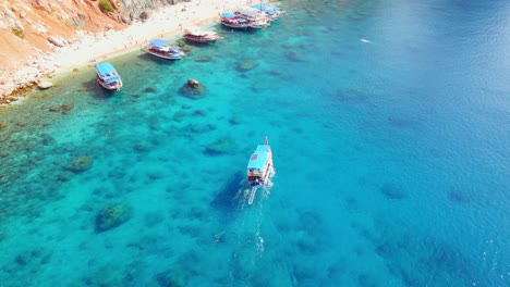 Aerial-4K-drone-view-of-a-boat-riding-to-the-Suluada-Island-in-Adrasan-Sea,-Antalya-–-Turkey