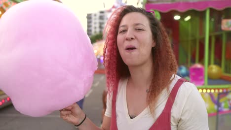 happy-woman-with-red-hair-eating-cotton-candy-at-the-fair
