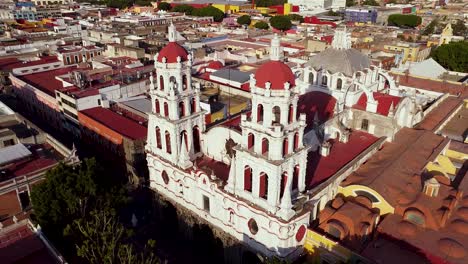 Iglesia-de-Compania-in-Puebla,-Mexico,-on-a-sunny-evening-surrounded-by-tightly-packed-buildings-in-a-dense-downtown-area