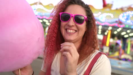 woman-with-cotton-candy-lowers-her-sunglasses-and-looks-at-the-camera-with-a-smile