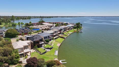 Aerial-rising-up-and-revealing-the-luxury-houses-and-apartments-on-the-shore-of-Lake-Mulwala,-NSW,-Australia