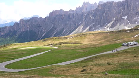 Cyclists-climbing-uphill-in-Giau-Pass,-rocky-mountain-range-background,-Italy