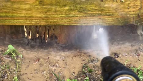Pressure-wash-reveals-termite-damage-in-base-of-wooden-fence-slow-motion