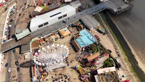 Southend-Adventure-Island-big-wheel-drone-fly-over-rotational-topdown-view,-camera-tilt-as-drone-passes-rides