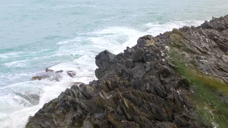 Generic-Cornish-coastline-of-sea-waves-crashing-into-rocks-in-Crantock-Cornwall