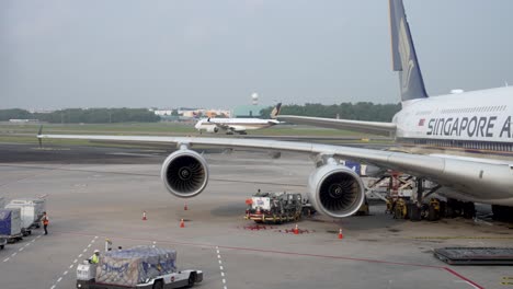 Airplane-A380-at-terminal-gate-at-the-Changi-airport,-people-workers-preparing-plane,-driving-cargo-lift