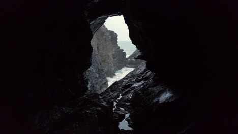 Cornwall-Crantock-view-of-rough-sea-and-rocks-through-a-cave-window-wide-shot