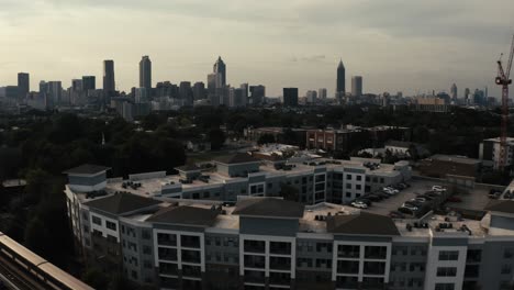 Der-U-Bahn-Zug-Marta-In-Atlanta,-Georgia,-Fährt-Im-Vordergrund-Eines-Apartmentkomplexes-Vorbei-Und-Zeigt-Eine-Wunderschöne-Luftaufnahme-Der-Skyline-Der-Innenstadt-Von-Atlanta
