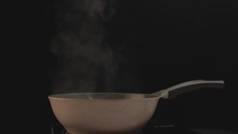 Allein-Stehende-Kochpfanne-Mit-Austretendem-Rauch-Und-Schwarzem-Hintergrund,-Aufgenommen-Auf-4K-Rohaufnahme