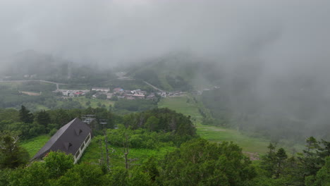 Aerial-tracking-shot-over-trees,-overlooking-slopes-of-Shiga-Kogen,-fog-in-Japan