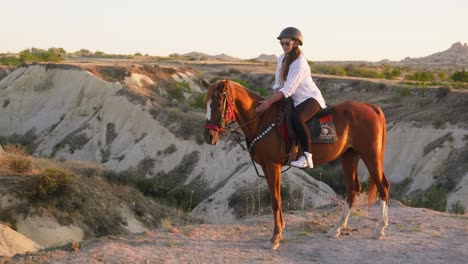 Young-woman-horseback-rider-enjoys-calm-peaceful-sunset-landscape