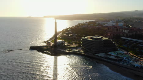 Beautiful-aerial-shot-in-orbit-during-the-sunset-of-the-Maspalomas-lighthouse,-with-beautiful-afternoon-colors