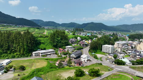 Aerial-view-backwards-over-a-rural-town,-sunny,-summer-day-in-Nagano,-Japan