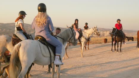 Tourist-guided-group-horseback-riding-Cappadocia-golden-hour-landscape