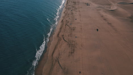 Luftaufnahme-Entlang-Der-Küste-Des-Strandes-Von-Maspalomas-Und-Zum-Blick-Auf-Den-Leuchtturm-Von-Maspalomas