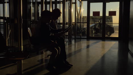Am-Flughafen-Von-Thessaloniki,-Griechenland,-Sitzt-Eine-Mutter-Mit-Ihrem-Sohn-Im-Wartezimmer-Und-Schaut-Sich-Videos-Auf-Einem-Tablet-An