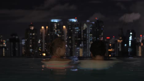 Im-Pool-Auf-Dem-Dach-Eines-Hotels-In-Kuala-Lumpur,-Malaysia,-Verliebtes-Paar-Mit-Blick-Auf-Die-Nächtliche-Stadt