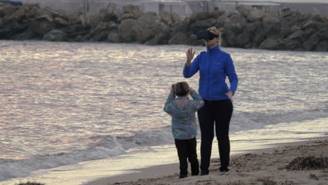 Mother-and-son-having-fun-with-VR-glasses-on-the-shore