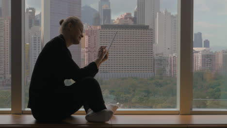 Woman-working-on-business-with-pad-sitting-by-the-window