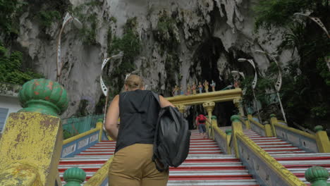 Young-woman-at-Batu-Caves-Malaysia-climbs-the-stairs-and-takes-pictures-on-tablet