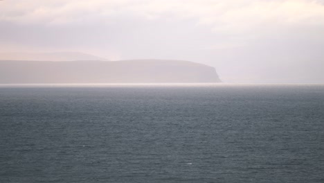 Rock-cliffs-in-Iceland-shrouded-in-white-mist-above-ocean-waters