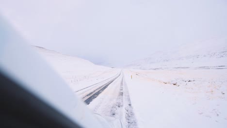 Passenger-view-from-car-driving-on-frozen-road-in-winter-mountains