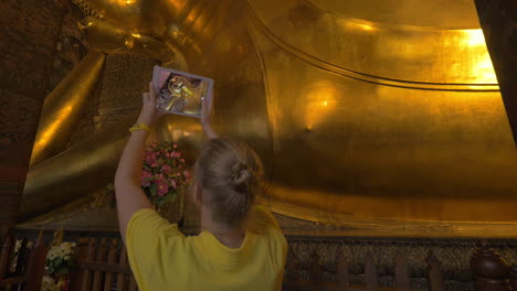 Tourist-with-pad-taking-photo-of-reclining-Buddha-statue-in-Bangkok