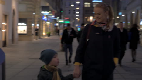 In-Vienna-Austria-in-evening-on-square-walking-a-young-mother-and-holding-hand-of-a-little-son