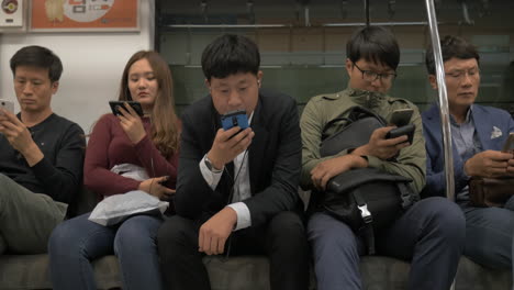 Pasajeros-Del-Metro-Que-Utilizan-Teléfonos-Móviles-Seúl,-Corea-Del-Sur
