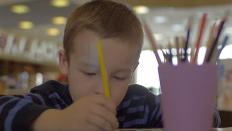 At-the-table-sitting-a-little-boy-and-draws-with-colored-pencils