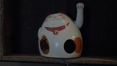 Ceramic-smiling-cat-with-swinging-hand-and-hieroglyph-on-the-black-shelf