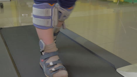 Close-up-view-of-small-boy-feet-on-treadmill-in-the-special-orthopedic-bandage-and-foot-wear