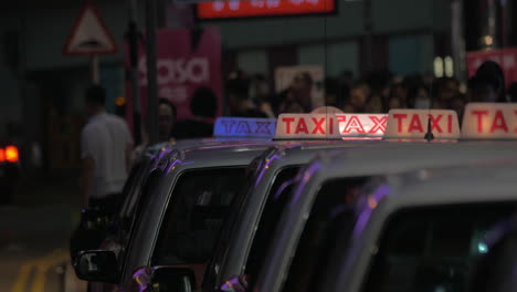 Night-view-of-taxi-sign-on-cabs-waiting-people
