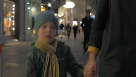 Child-walking-with-mother-in-evening-city-street