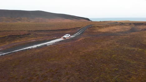 SUV-car-driving-through-mud-puddle-on-gravel-road-in-nordic-landscape