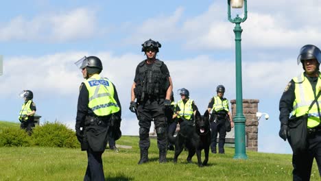 Police-captain-directs-people-on-grassy-hillside-with-trained-k9-dog-unit